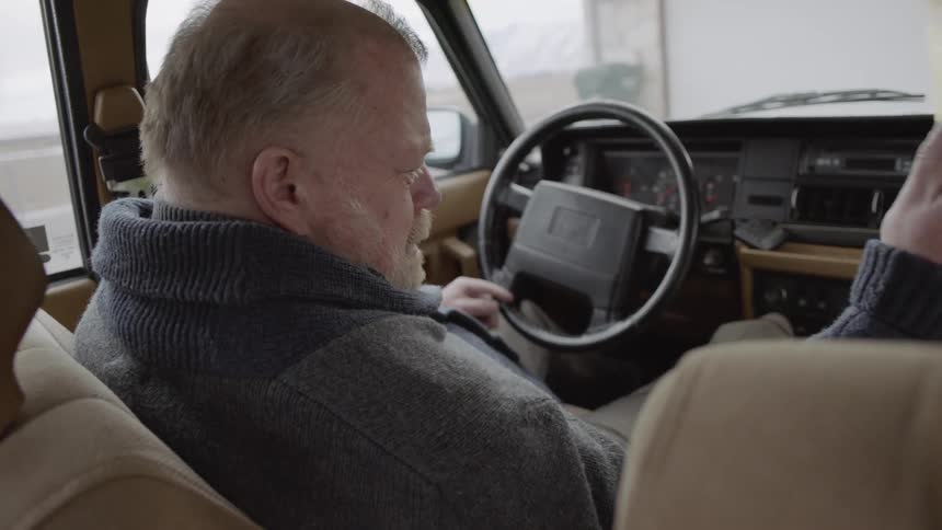 A man sitting in the car hands off some items to the person next to him