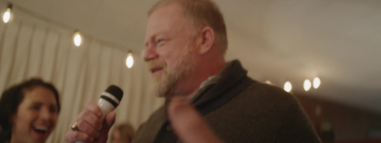 Man talks into a microphone at a party