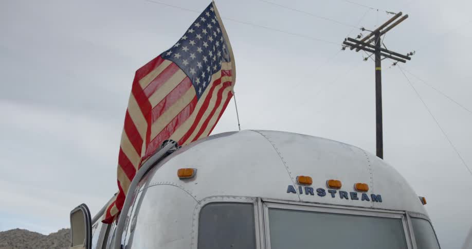 American flag waves in the wind over a camper