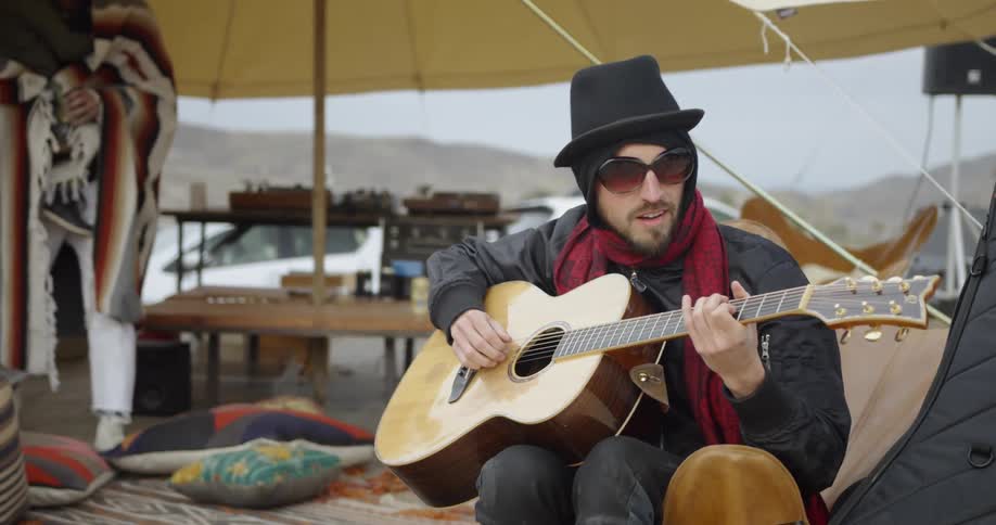 Man sits under canopy playing guitar