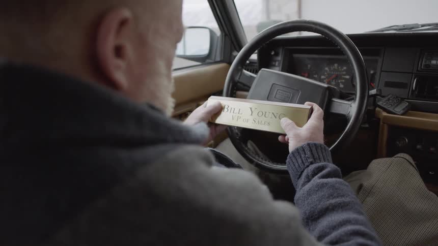 Man looks at a nameplate while sitting in a parked car