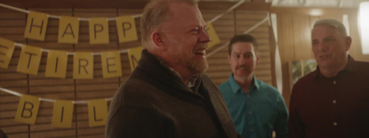 A man laughs while holding a cake for a celebration