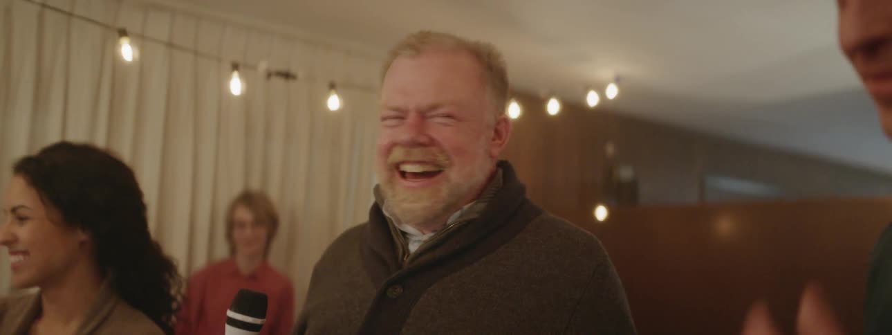 An elderly man smiles at a gathering