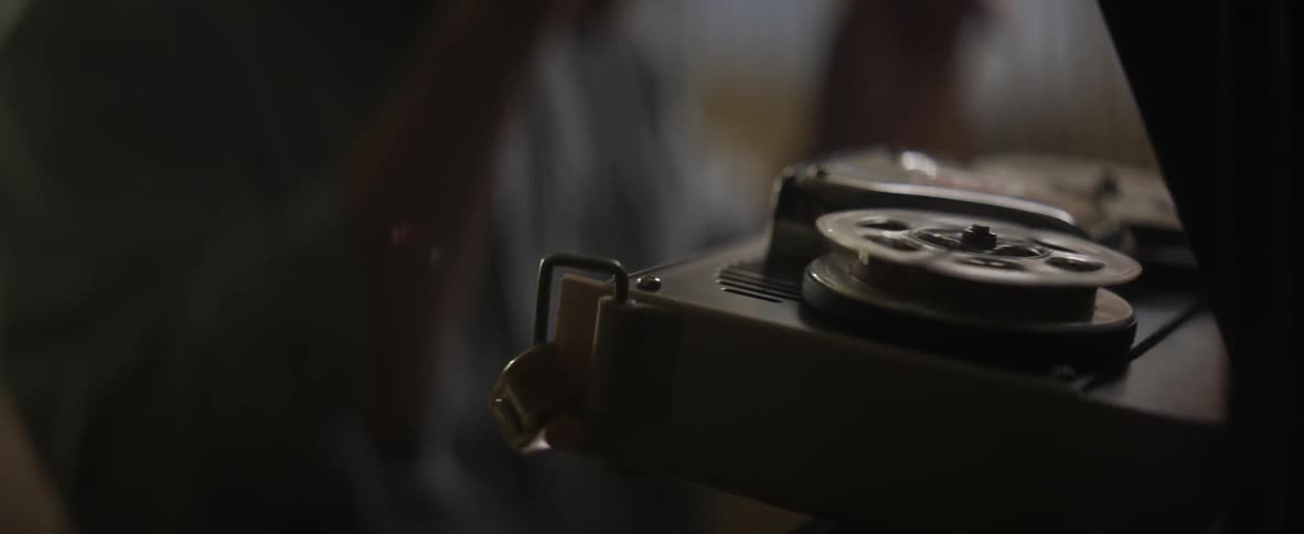 A person looking at a reel to reel machine