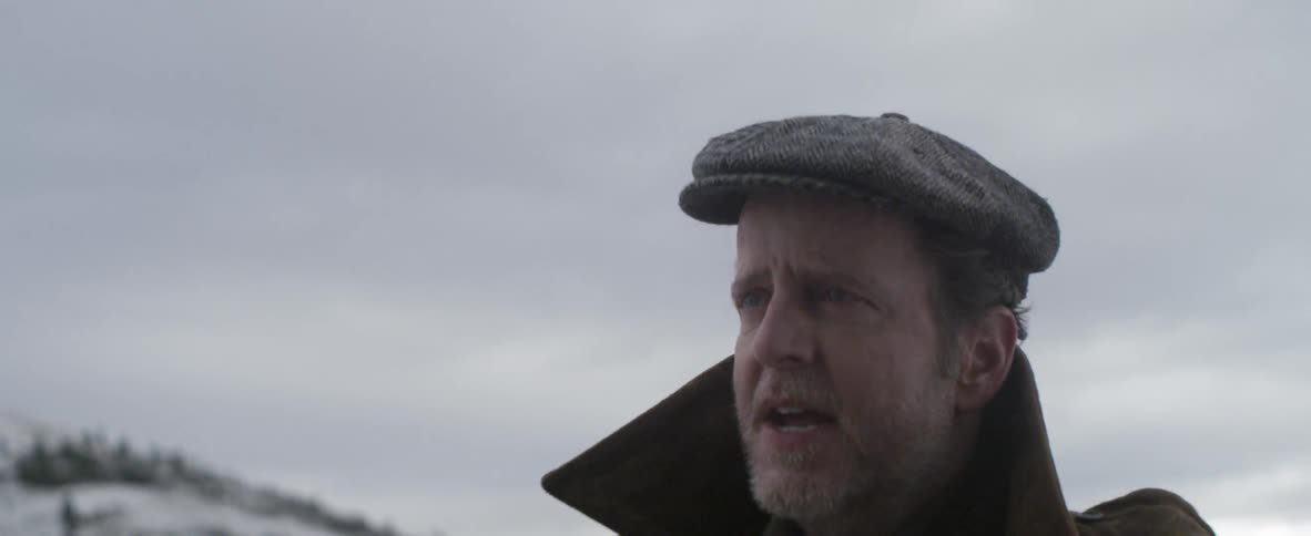 A bearded man in a hat walks in the snow