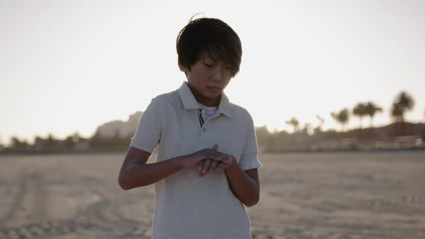 A child rubs his hands on the beach