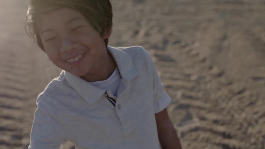 Boy smiles and swings his arms in a dirt field