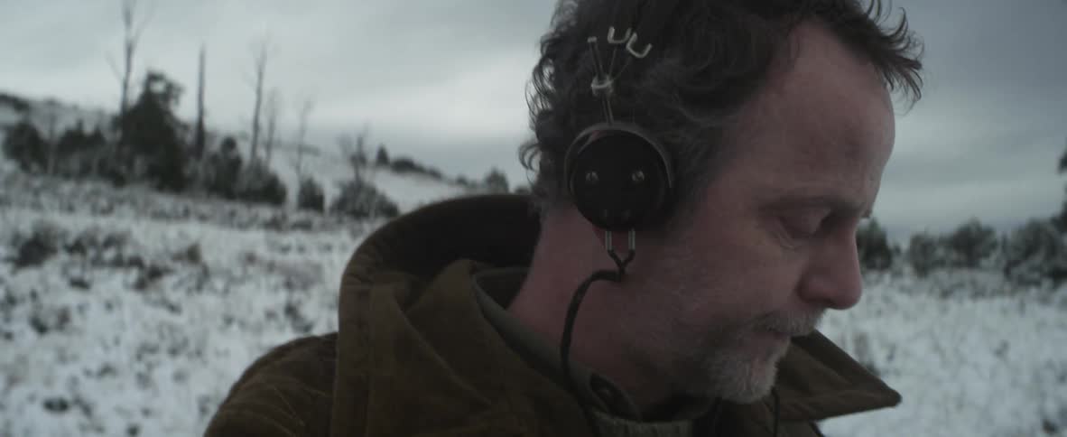 A man with headphones standing in a snowy field