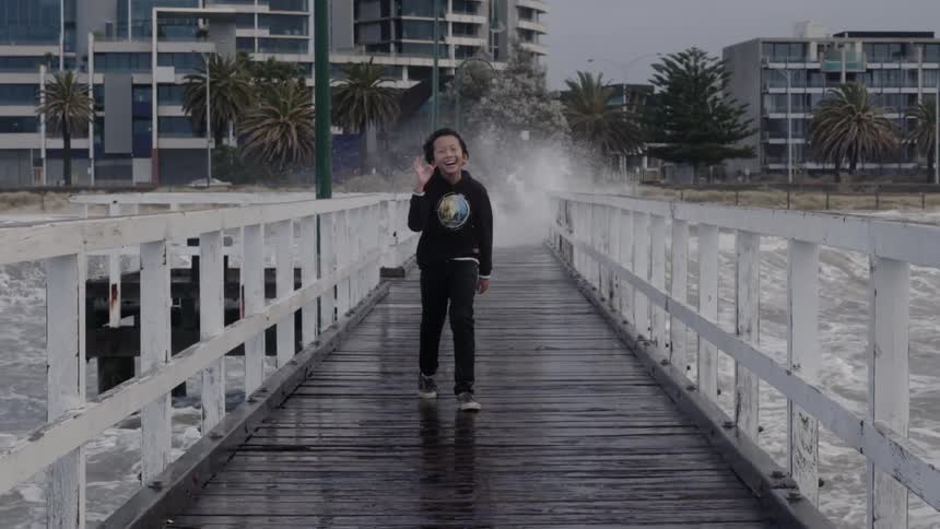 A child walks down the pier as waves hit it