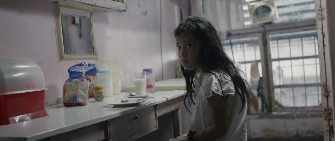 A young girl eats at a desk