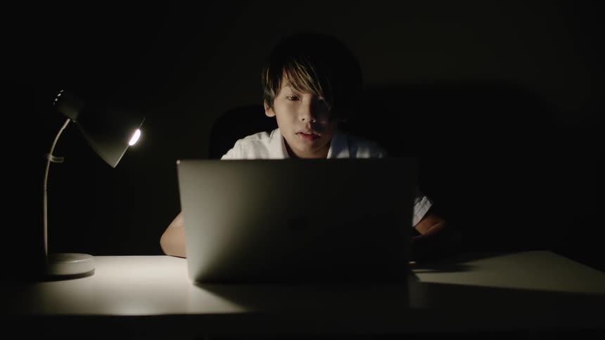 A young boy types on a laptop