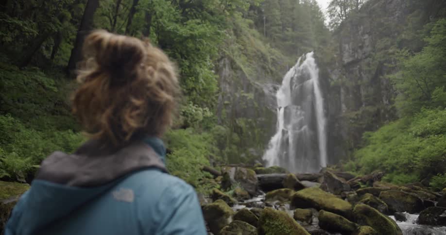 Woman in nature staring at a cascade