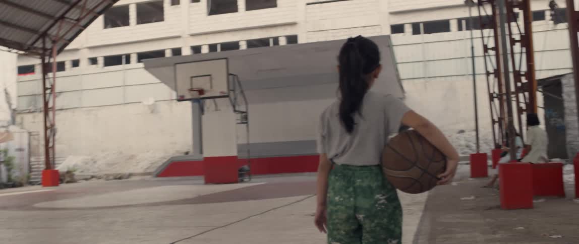 A girl carries a basketball on the court