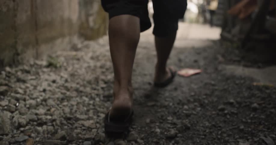 A man in sandals walks down the alley