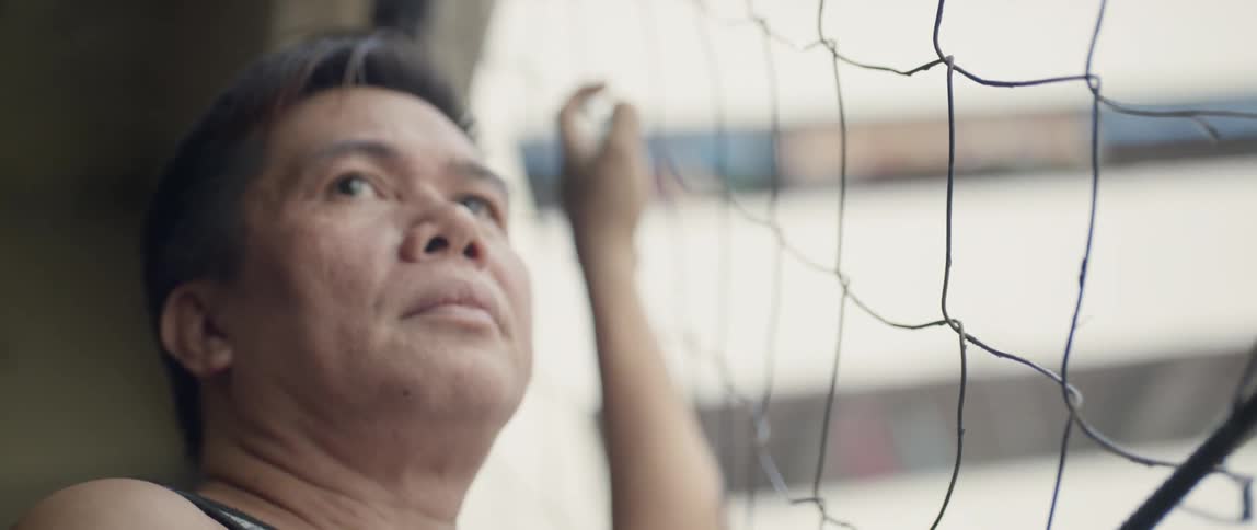 The man hangs on the fence of the balcony