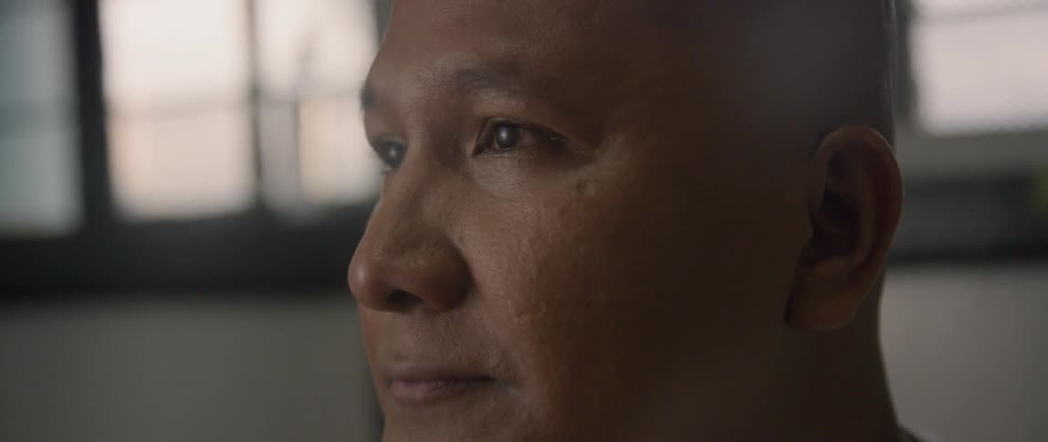 A man looks ahead while sunlight comes in through windows behind him