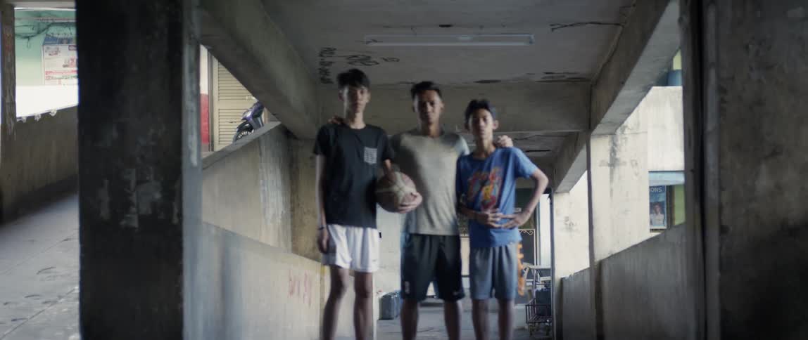 Man holds a basketball as two other men stand next to him as they pose for a photo