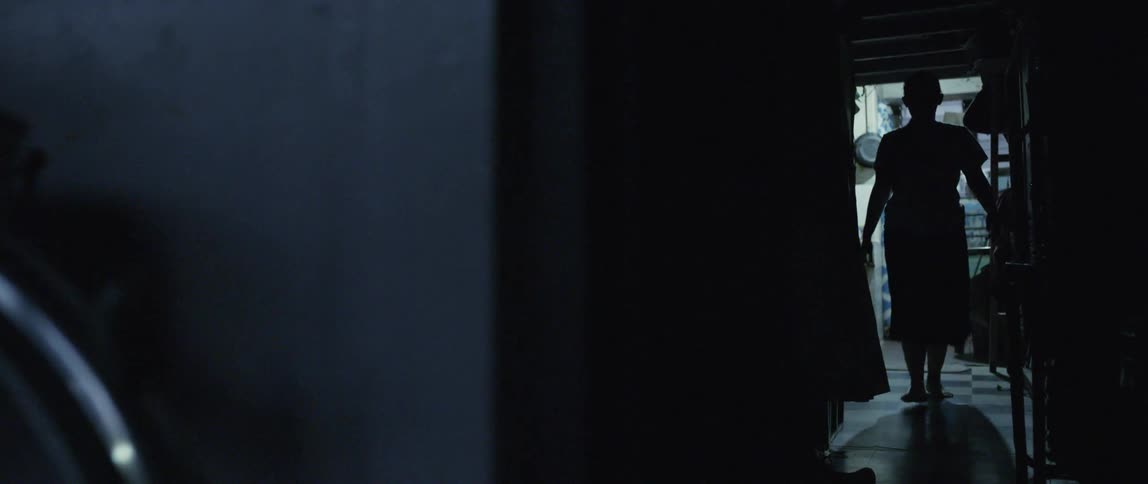 A woman walks down the dark hall