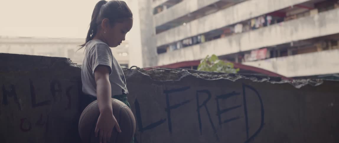 Young girl stands looking down as she holds a basketball