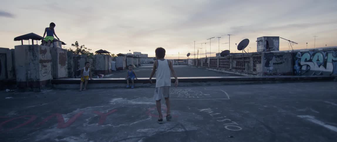 The child walks towards others on the rooftop