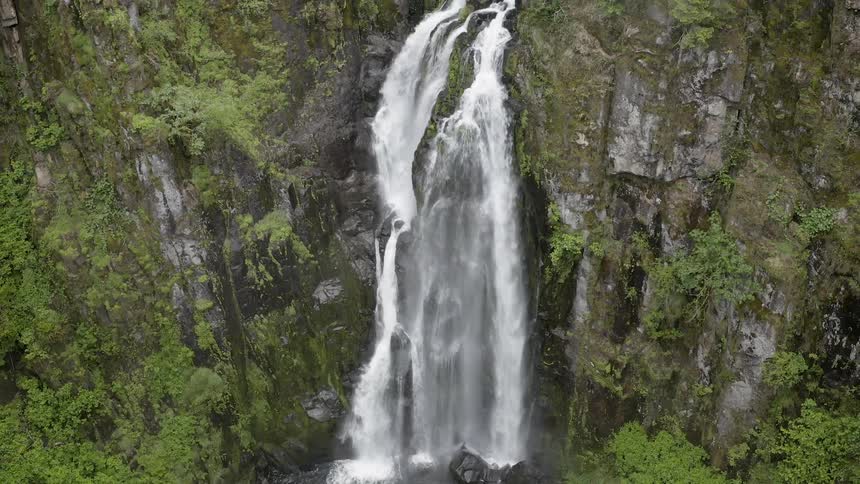 A waterfall flows over a cliff into a creek below