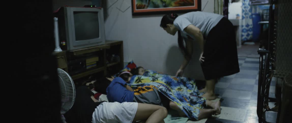 A woman wakes children sleeping on a floor