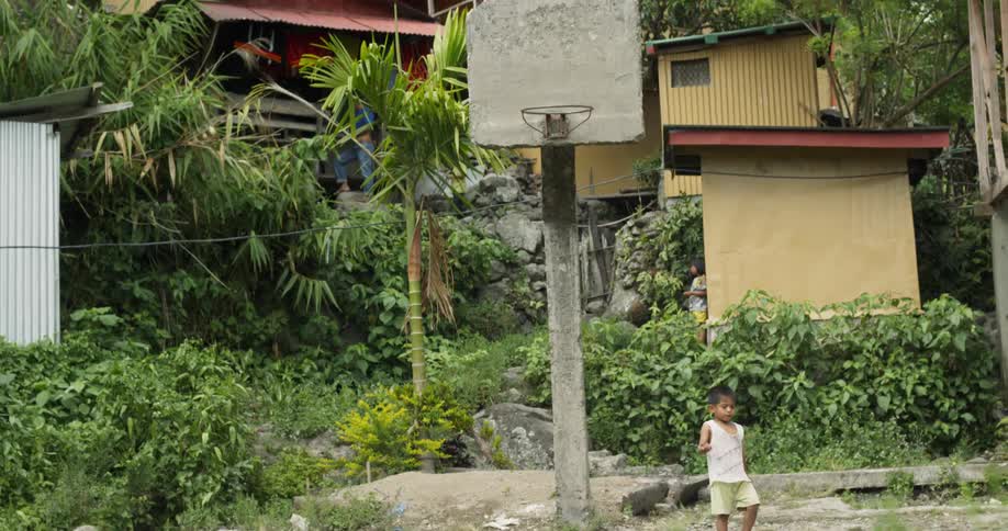 Child walks by a basketball hoop in a village