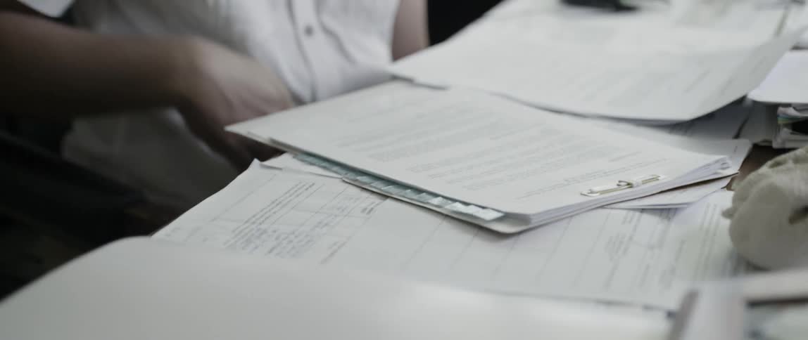 Documents cover a man's desk