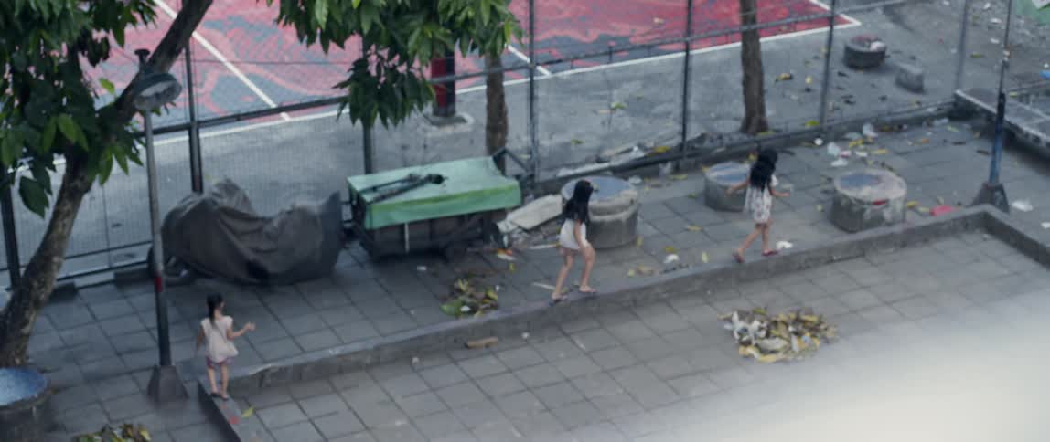 Children run past the fence near the basketball court