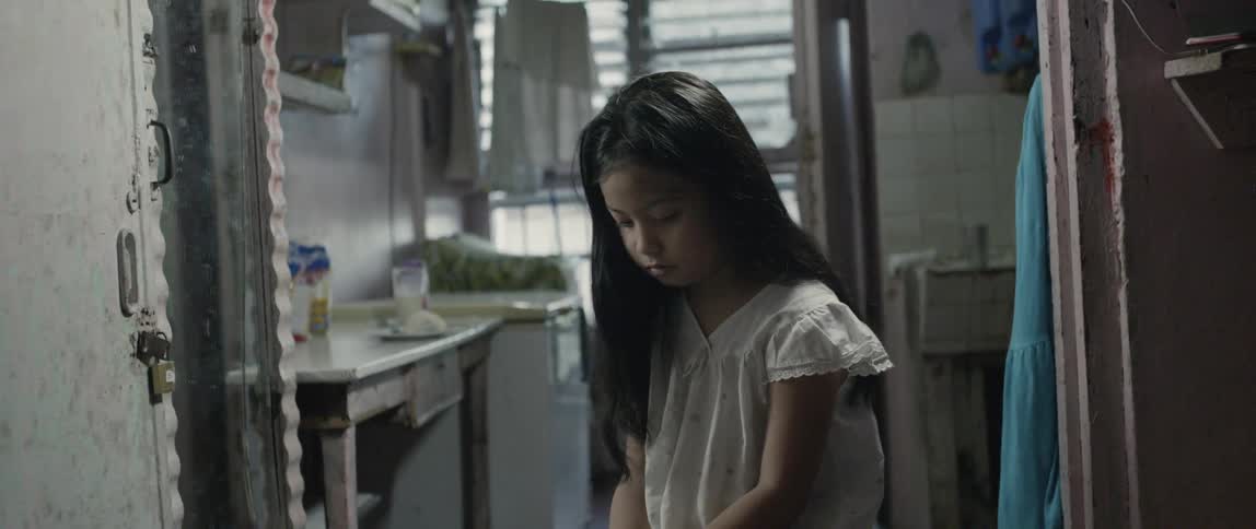 Young girl looks down as she stands in a house