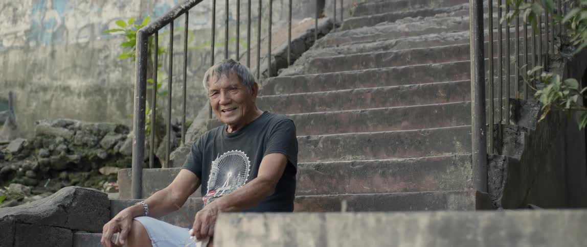The man sits on the stone steps smiling