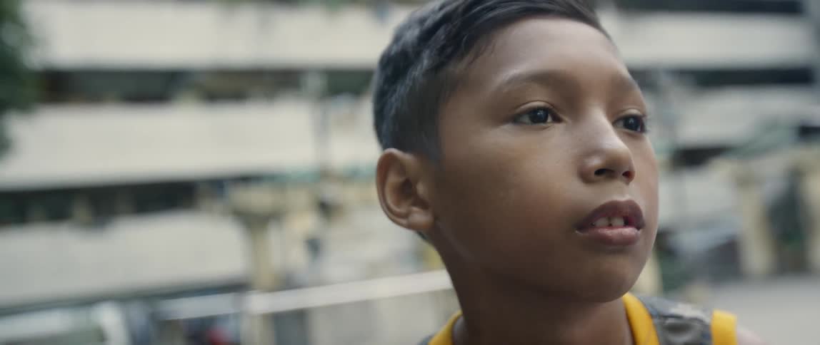 Child stands outside near a building in a city