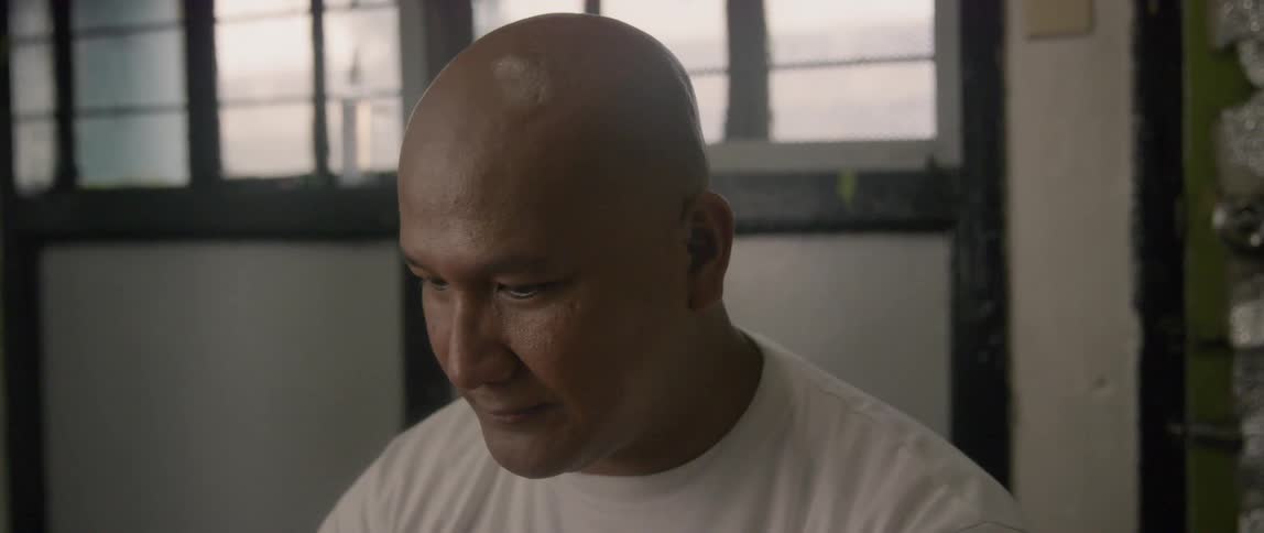 A man sits in his home smiling and looking around