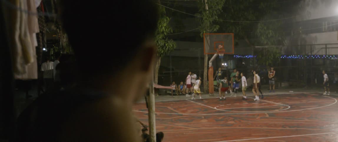 Children watch a basketball game at night