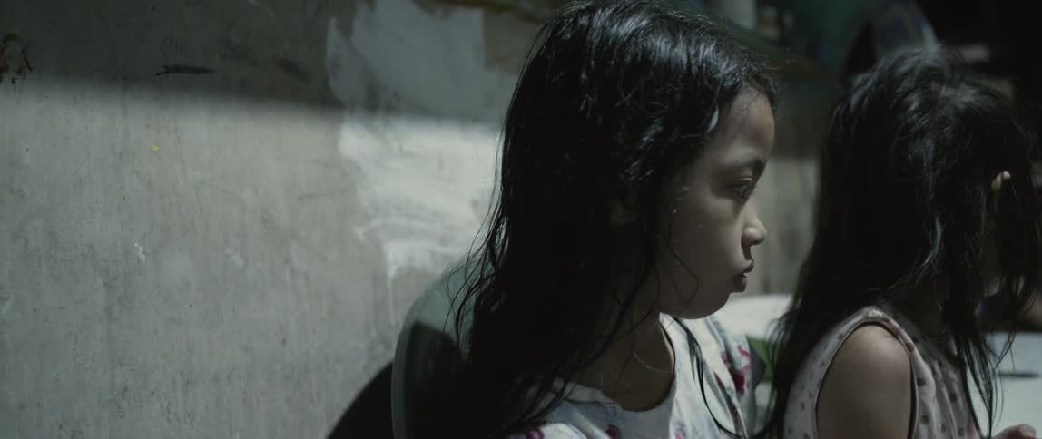 The children are sitting by the concrete wall