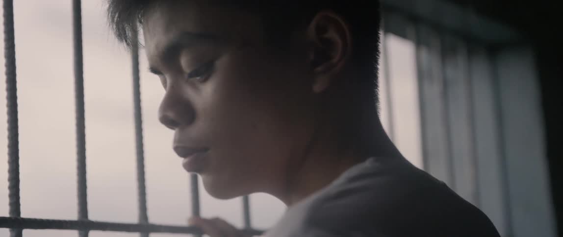 A boy leans against the gate of the window