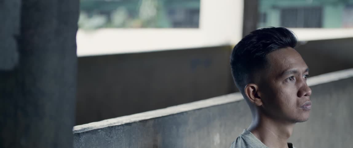 Man sits next to a concrete wall
