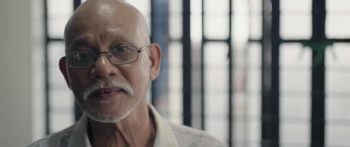 Elderly man stands in front of a window