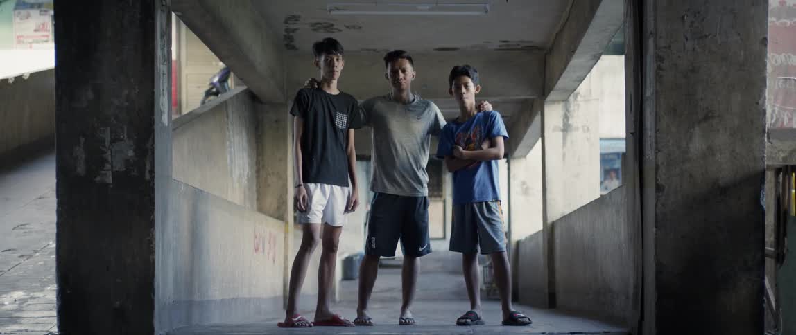 Three teenagers stand in an open air building