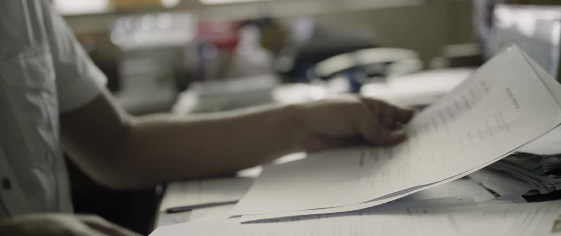 Person sits at a table reading some papers