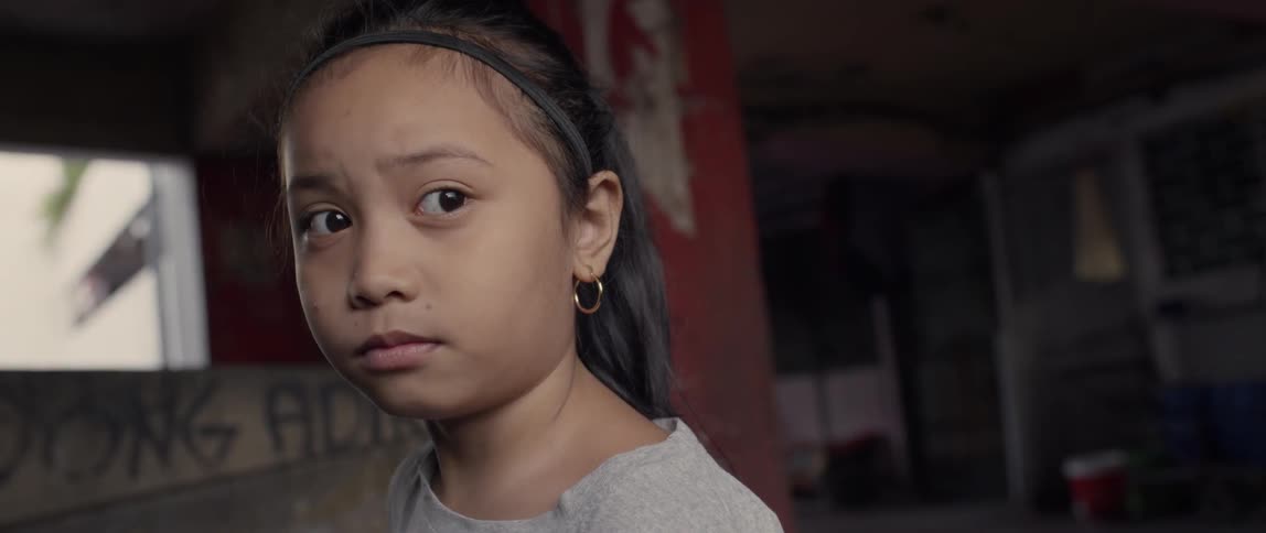 A young girl looks sad in a concrete building