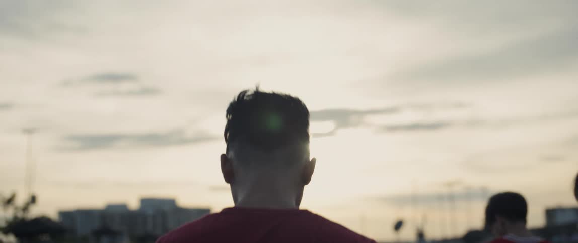 Man in a red shirt walks under the cloudy sky