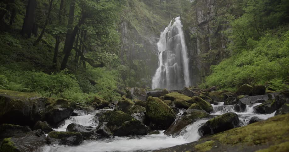 A waterfall flowing over a cliff and through rocks in a forest