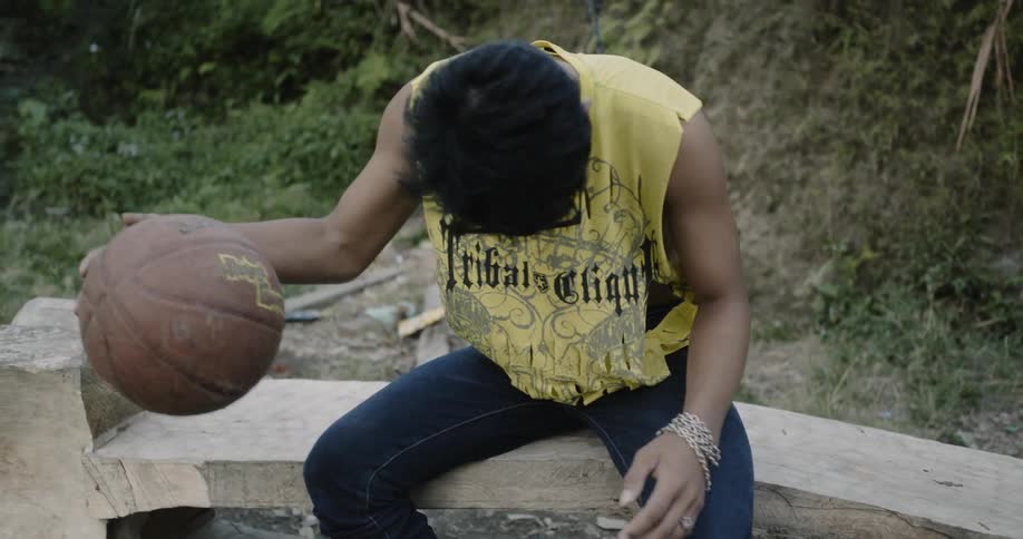 A man bounces the basketball while seated