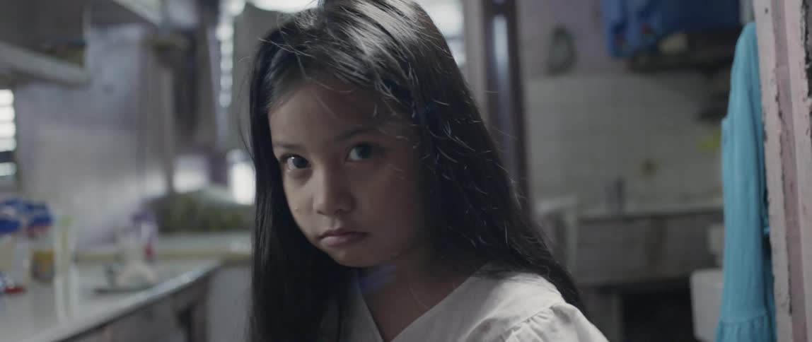 A child looks up while sitting in the kitchen