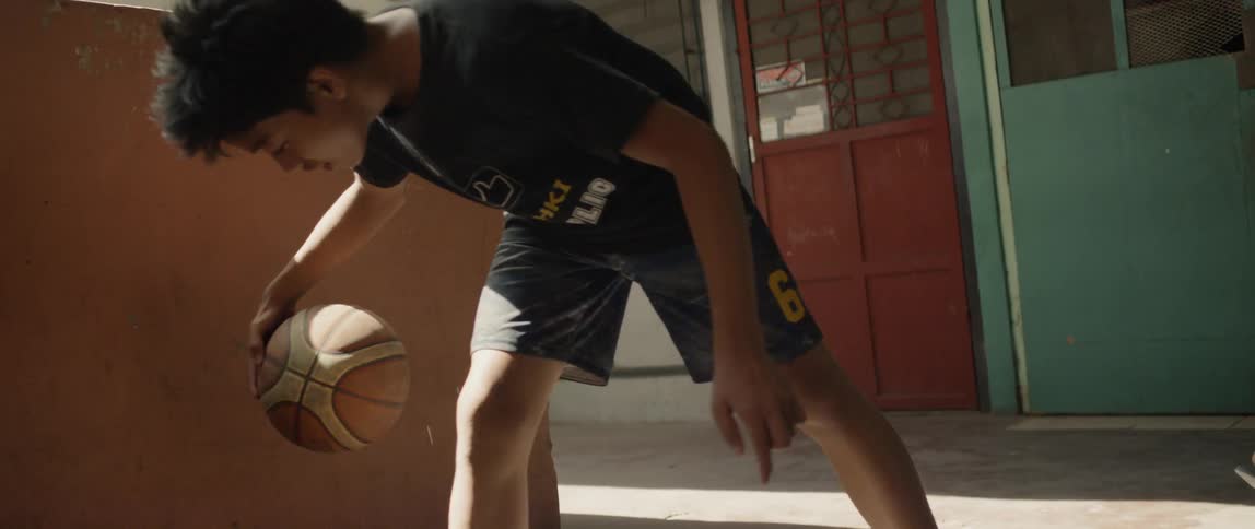 Boy dribbles a basketball on concrete