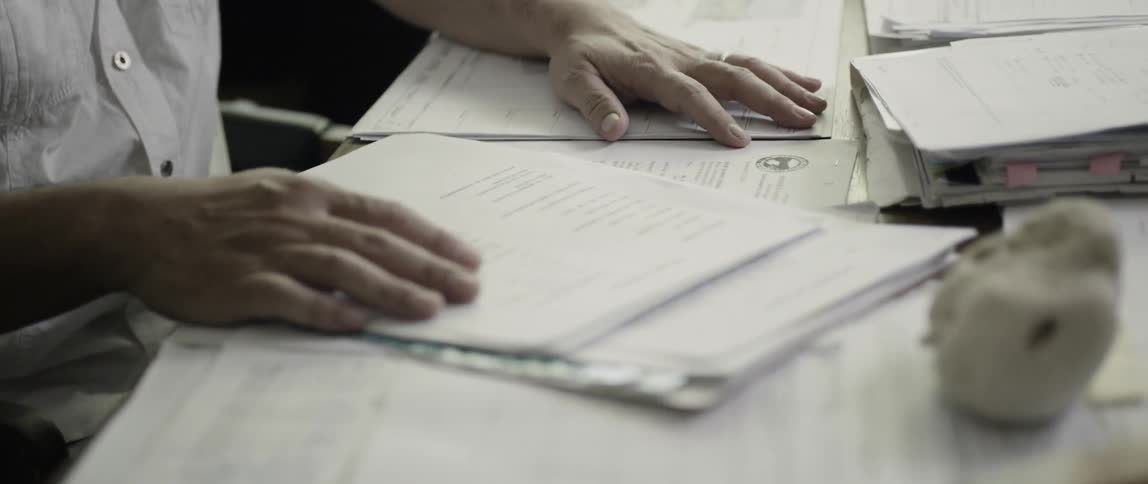 Documents cover a man's desk