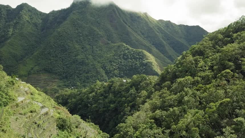 Clouds roll over the top of a grassy mountain