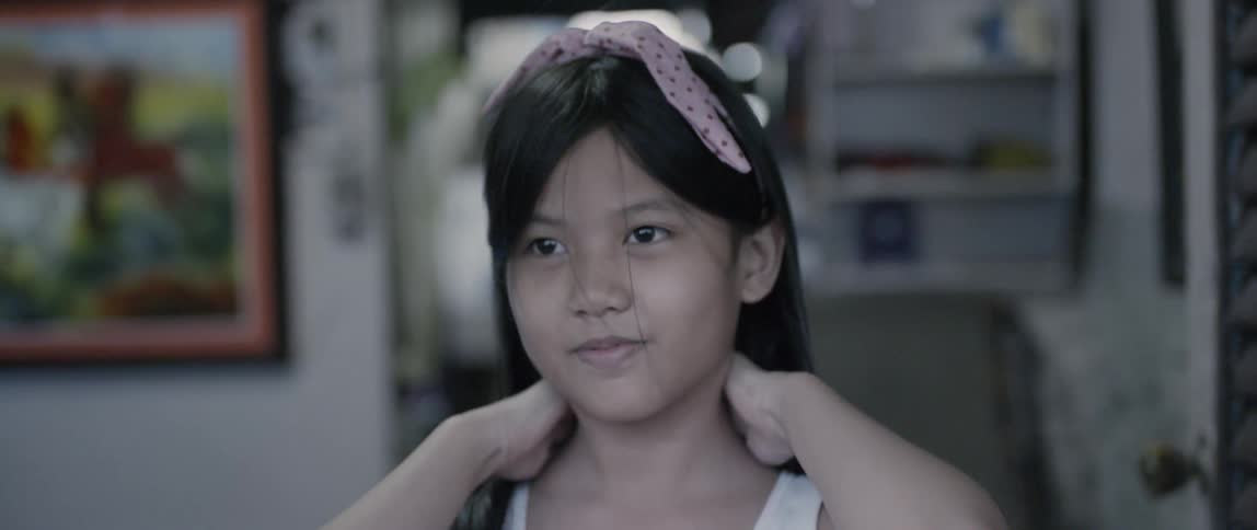 A girl with a bow in her hair drops her hands and smiles