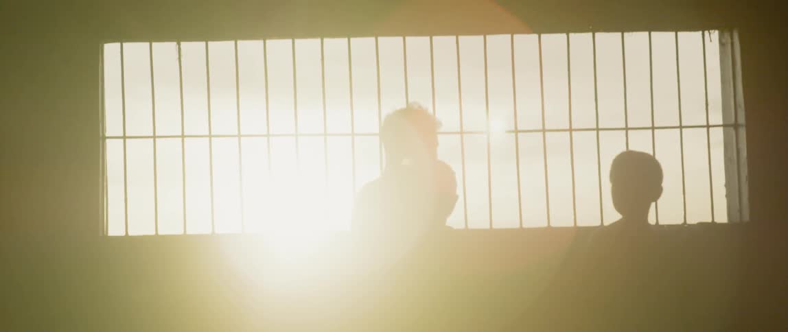 Boys stand in front of a window at sunset